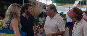 Movie still from “Adrift” (2018), directed by Baltasar Kormákur – Two men talking to each other at an outdoor market; Medium shot, Over the shoulder angle