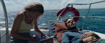 Movie still from “Adrift” (2018), directed by Baltasar Kormákur – A man laying on a boat next to a woman on a boat; Medium shot, High angle