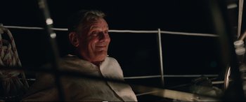 Movie still from “Adrift” (2018), directed by Baltasar Kormákur – An older man sitting in front of a white fence at night; Close Up shot, Over the shoulder angle