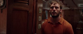 Movie still from “Adrift” (2018), directed by Baltasar Kormákur – A man standing in front of a mirror in a room; Medium shot, Over the shoulder angle