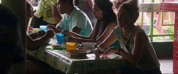 Movie still from “Adrift” (2018), directed by Baltasar Kormákur – A group of people sitting at a table with plates of food on it; Medium shot, Over the shoulder angle