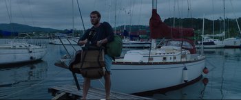 Movie still from “Adrift” (2018), directed by Baltasar Kormákur – A man walking on a dock with a boat in the background; Wide shot, Low angle