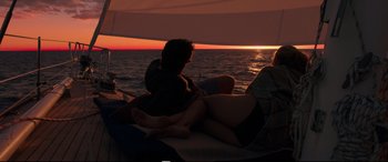 Movie still from “Adrift” (2018), directed by Baltasar Kormákur – A man and a woman sitting on a boat at sunset; Wide shot, High angle