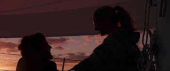 Movie still from “Adrift” (2018), directed by Baltasar Kormákur – Two people standing in front of a window at sunset; Medium shot, Low angle