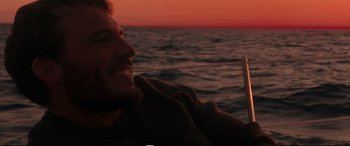 Movie still from “Adrift” (2018), directed by Baltasar Kormákur – A man smiles while sitting on a boat in the ocean; Close Up shot, Over the shoulder angle