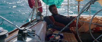 Movie still from “Adrift” (2018), directed by Baltasar Kormákur – A man sitting on the deck of a sailboat in the water; Medium shot, High angle