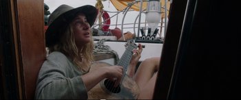 Movie still from “Adrift” (2018), directed by Baltasar Kormákur – A woman sitting on a boat playing a guitar; Medium shot, Low angle