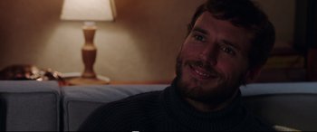 Movie still from “Adrift” (2018), directed by Baltasar Kormákur – A person sitting on a bed smiling; Close Up shot, Over the shoulder angle
