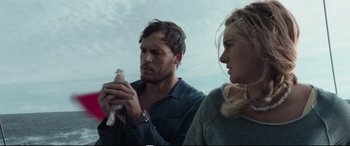 Movie still from “Adrift” (2018), directed by Baltasar Kormákur – A man and a woman standing next to each other holding a bird; Close Up shot, Low angle