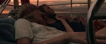 Movie still from “Adrift” (2018), directed by Baltasar Kormákur – A man and a woman laying on a bed next to a body of water; Medium shot, High angle