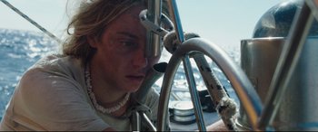 Movie still from “Adrift” (2018), directed by Baltasar Kormákur – A young man is looking at the camera through a rope; Close Up shot, High angle