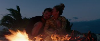 Movie still from “Adrift” (2018), directed by Baltasar Kormákur – A man and a woman sitting next to each other near a fire pit; Medium shot, High angle