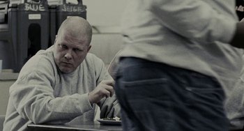 Movie still from “Adulthood” (2008), directed by Noel Clarke – A man sitting at a table in front of another man; Medium shot, Over the shoulder angle