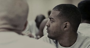 Movie still from “Adulthood” (2008), directed by Noel Clarke – A black and white photo of a man looking up; Close Up shot, Over the shoulder angle