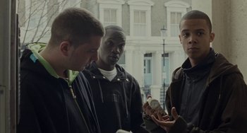 Movie still from “Adulthood” (2008), directed by Noel Clarke – A group of young men standing next to each other on the street; Medium shot, Over the shoulder angle
