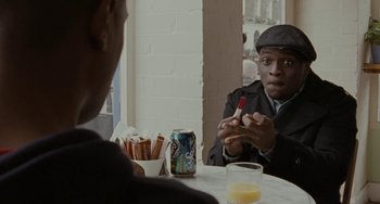 Movie still from “Adulthood” (2008), directed by Noel Clarke – A man sitting at a table with a can of soda; Close Up shot, Over the shoulder angle