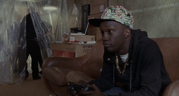 Movie still from “Adulthood” (2008), directed by Noel Clarke – A man sitting on a couch holding a game controller in his hand; Close Up shot, High angle