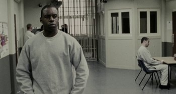 Movie still from “Adulthood” (2008), directed by Noel Clarke – A man standing in a jail cell with his hands in his pockets; Medium shot, Low angle