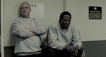 Movie still from “Adulthood” (2008), directed by Noel Clarke – A couple of men sitting next to each other on a bench; Medium shot, Low angle