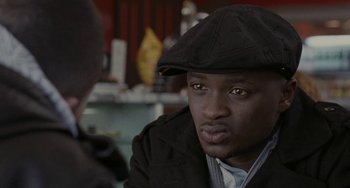 Movie still from “Adulthood” (2008), directed by Noel Clarke – A person wearing a hat and jacket; Close Up shot, Over the shoulder angle