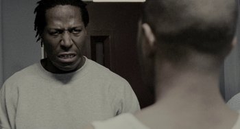 Movie still from “Adulthood” (2008), directed by Noel Clarke – A man looking at himself in the mirror in front of a mirror; Close Up shot, Over the shoulder angle