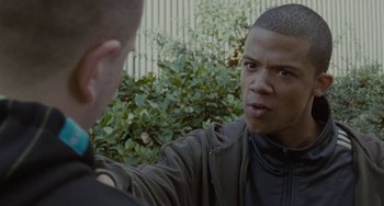 Movie still from “Adulthood” (2008), directed by Noel Clarke – A man talking to another man in front of a fence; Close Up shot, Over the shoulder angle
