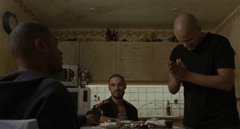 Movie still from “Adulthood” (2008), directed by Noel Clarke – A group of people sitting at a table in a kitchen; Medium shot, Over the shoulder angle