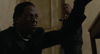 Movie still from “Adulthood” (2008), directed by Noel Clarke – A man in a black suit is holding a cell phone; Close Up shot, Low angle