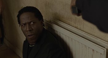 Movie still from “Adulthood” (2008), directed by Noel Clarke – A man in a black suit is leaning against a wall; Close Up shot, Low angle