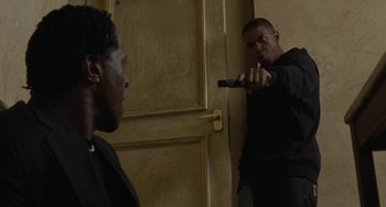 Movie still from “Adulthood” (2008), directed by Noel Clarke – A man holding a knife in front of another man in front of a door; Medium shot, Over the shoulder angle