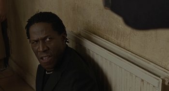 Movie still from “Adulthood” (2008), directed by Noel Clarke – A man in a black suit standing in front of a wall; Close Up shot, Low angle