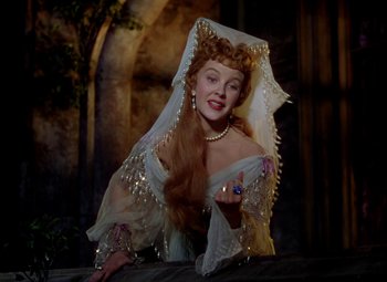 Movie still from “Adventures of Don Juan” (1948), directed by Vincent Sherman – A woman dressed as a princess holding a candle; Medium shot, Over the shoulder angle