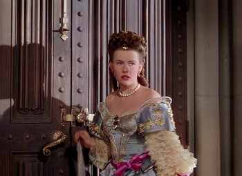 Movie still from “Adventures of Don Juan” (1948), directed by Vincent Sherman – A woman dressed as a princess in front of a door; Medium shot, Over the shoulder angle