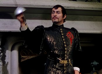 Movie still from “Adventures of Don Juan” (1948), directed by Vincent Sherman – A man dressed in a black and gold outfit holding a silver object; Medium shot, Low angle