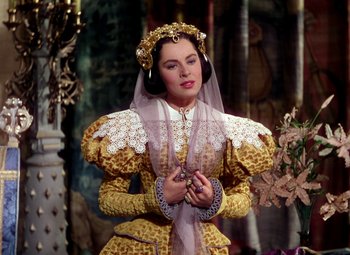 Movie still from “Adventures of Don Juan” (1948), directed by Vincent Sherman – A woman dressed as a queen in a costume; Medium shot, Over the shoulder angle