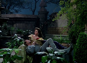 Movie still from “Adventures of Don Juan” (1948), directed by Vincent Sherman – A man and a woman laying on the ground in a garden; Wide shot, High angle