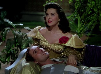 Movie still from “Adventures of Don Juan” (1948), directed by Vincent Sherman – A man and a woman are sitting on a bed; Medium shot, High angle