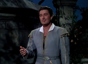 Movie still from “Adventures of Don Juan” (1948), directed by Vincent Sherman – A man in a gray and white outfit standing in front of a building; Medium shot, Low angle