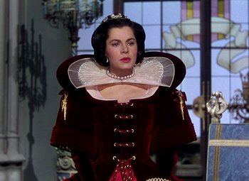 Movie still from “Adventures of Don Juan” (1948), directed by Vincent Sherman – A woman wearing a red dress and a white collar; Medium shot, Over the shoulder angle