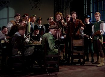Movie still from “Adventures of Don Juan” (1948), directed by Vincent Sherman – A group of people sitting and standing around each other; Wide shot, High angle