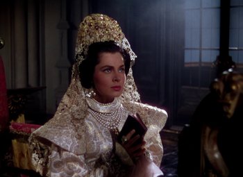 Movie still from “Adventures of Don Juan” (1948), directed by Vincent Sherman – A woman in a white dress holding a cell phone; Close Up shot, Over the shoulder angle
