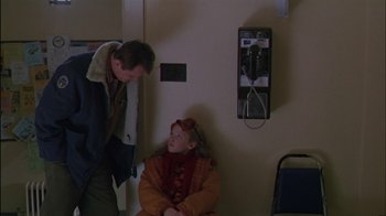 Movie still from “Affliction” (1997), directed by Paul Schrader – A man standing next to a woman sitting on a chair; Medium shot, Over the shoulder angle