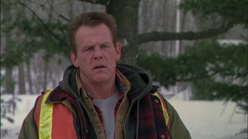 Movie still from “Affliction” (1997), directed by Paul Schrader – A man in a plaid jacket standing next to a tree; Close Up shot, Over the shoulder angle