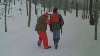 Movie still from “Affliction” (1997), directed by Paul Schrader – Two people walking in the snow near a forest; Wide shot, Over the shoulder angle