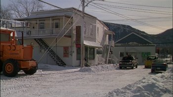 Movie still from “Affliction” (1997), directed by Paul Schrader – A truck parked in front of a building on a snowy day; Extreme Wide shot, High angle