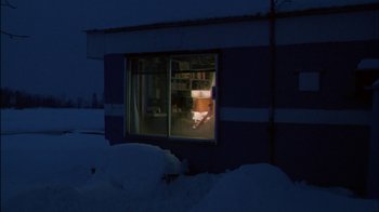 Movie still from “Affliction” (1997), directed by Paul Schrader – A window of a building in the snow at night time; Extreme Wide shot, Low angle