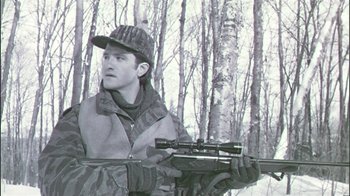 Movie still from “Affliction” (1997), directed by Paul Schrader – A man holding a rifle in a wooded area; Medium shot, Low angle
