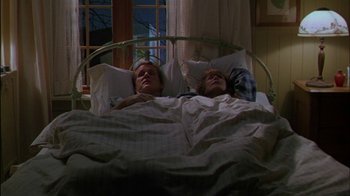 Movie still from “Affliction” (1997), directed by Paul Schrader – Two people laying in a bed in a room; Wide shot, High angle