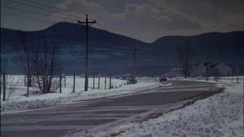 Movie still from “Affliction” (1997), directed by Paul Schrader – A car driving down a snow covered road; Extreme Wide shot, High angle
