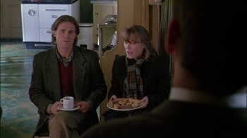 Movie still from “Affliction” (1997), directed by Paul Schrader – A man and a woman sitting in front of each other holding plates of food; Medium shot, Over the shoulder angle